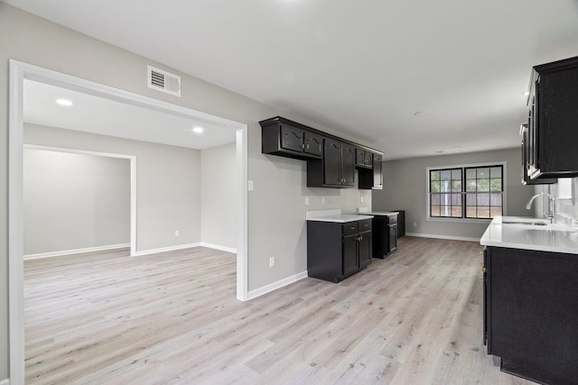 6410 Coteswood Rd, Memphis, TN 38134 - kitchen featuring a sink, light wood finished floors, light countertops, baseboards, and dark cabinets