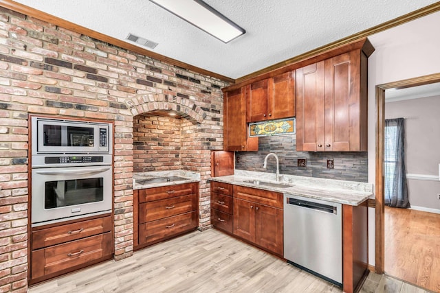 858 Gunnison Dr, Collierville, TN 38017 - kitchen featuring stainless steel appliances, a sink, light wood-type flooring, a textured ceiling, and light stone countertops