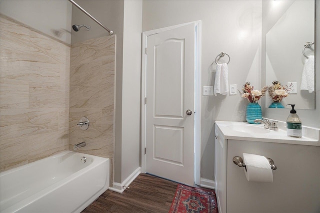 bathroom with washtub / shower combination, wood finished floors, vanity, and baseboards