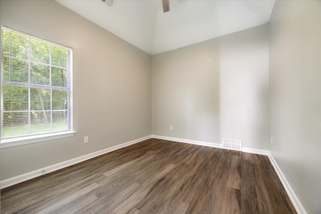 unfurnished room with dark wood-style floors, healthy amount of natural light, vaulted ceiling, and baseboards