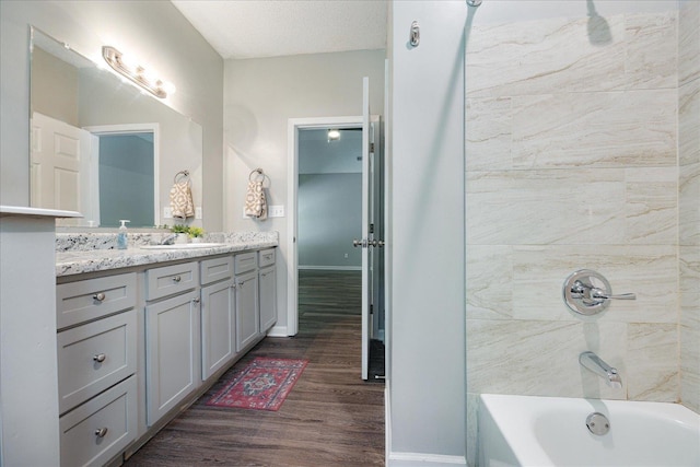 bathroom with wood finished floors, vanity, shower / washtub combination, and baseboards