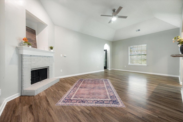unfurnished living room featuring a ceiling fan, wood finished floors, a brick fireplace, arched walkways, and lofted ceiling