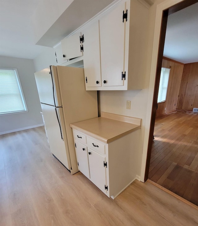 5551 Derron Dr, Memphis, TN 38115 - kitchen with light wood-style floors, white cabinets, light countertops, baseboards, and wood walls