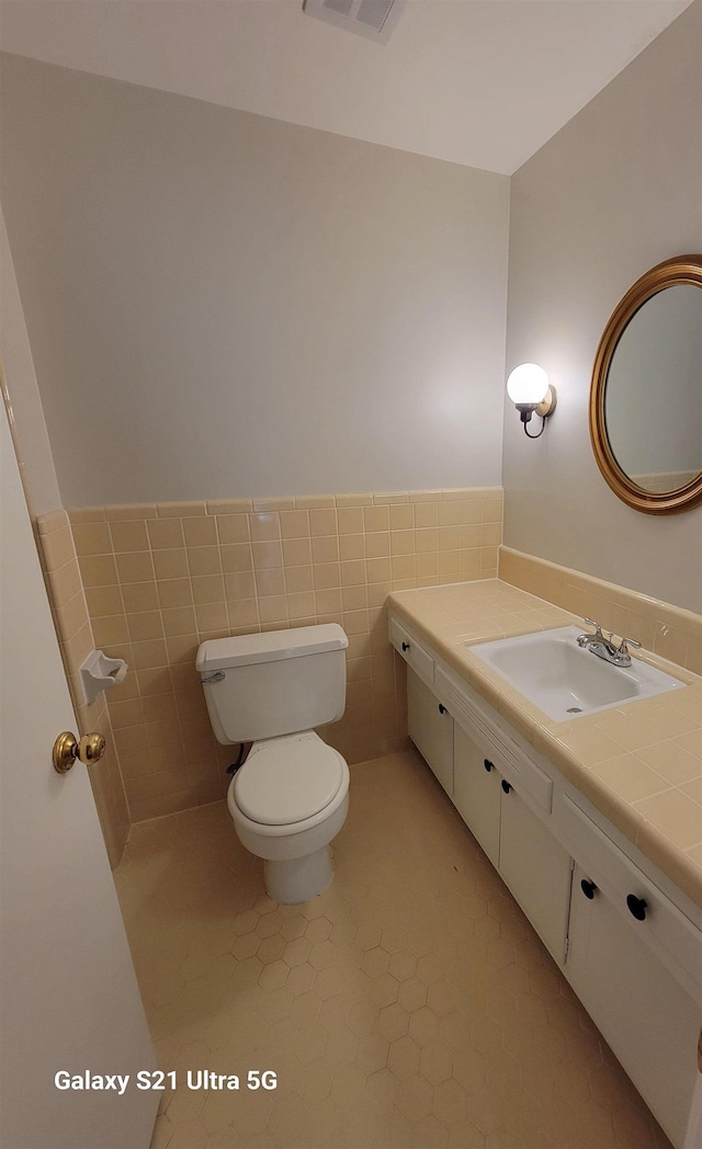 5551 Derron Dr, Memphis, TN 38115 - bathroom with toilet, vanity, a wainscoted wall, tile walls, and tile patterned flooring