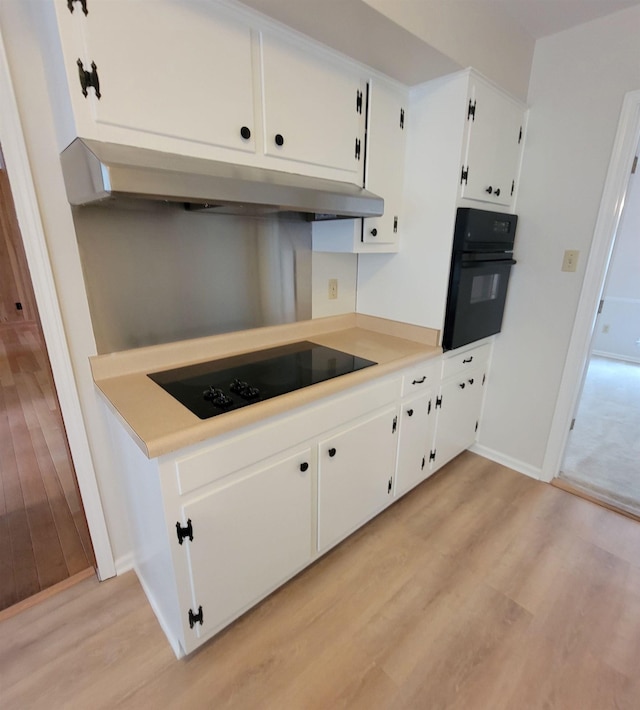 5551 Derron Dr, Memphis, TN 38115 - kitchen featuring black appliances, under cabinet range hood, light wood-type flooring, white cabinetry, and baseboards