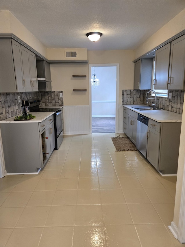 3403 Lynchburg St, Memphis, TN 38134 - kitchen with appliances with stainless steel finishes, gray cabinets, a sink, backsplash, and a textured ceiling