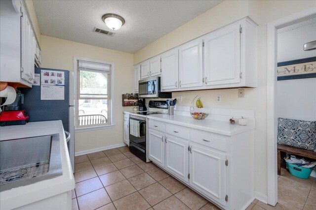 4357 Water Briar Rd, Millington, TN 38053 - kitchen with range with electric stovetop, stainless steel microwave, white cabinetry, light tile patterned floors, and a textured ceiling