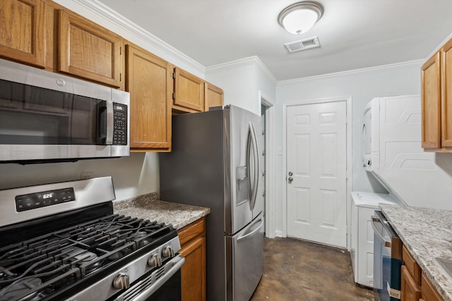 1000 S Cox St, Memphis, TN 38104 - kitchen with stainless steel appliances, estacked washer and dryer, concrete flooring, ornamental molding, and light stone counters