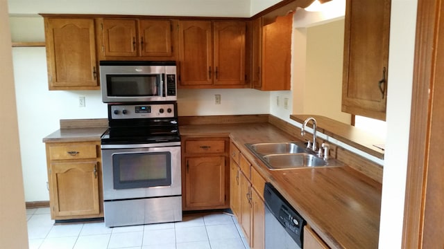 6240 Kirby Downs Dr, Memphis, TN 38115 - kitchen featuring stainless steel appliances, a sink, light tile patterned floors, and brown cabinets