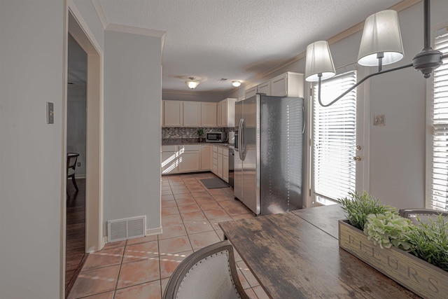 8451 Donegal Cv, Germantown, TN 38139 - kitchen featuring stainless steel appliances, light tile patterned floors, backsplash, white cabinetry, and a textured ceiling