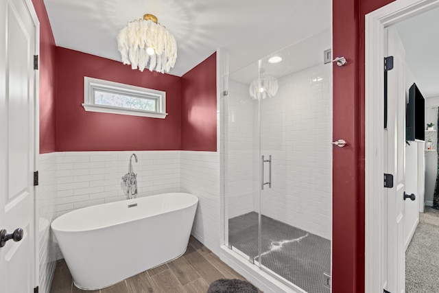 1002 New York St, Memphis, TN 38104 - bathroom with a freestanding tub, a stall shower, a chandelier, a wainscoted wall, and wood finished floors