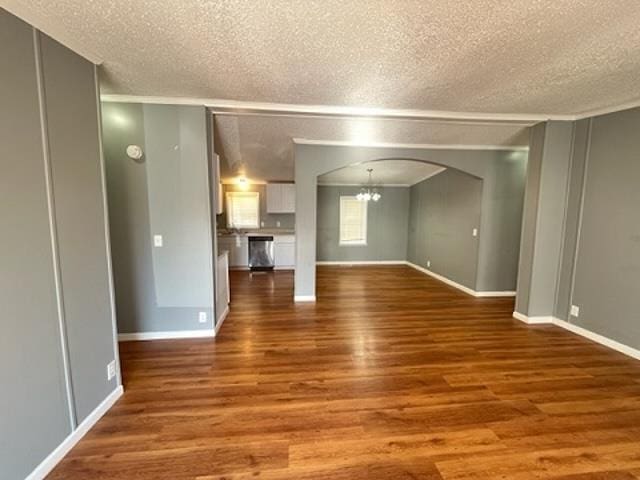 4472 Cedar Ridge Ln, Unicorp/Memphis, TN 38128 - unfurnished living room featuring a chandelier, arched walkways, a textured ceiling, dark wood-type flooring, and baseboards