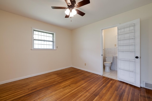 5151 Canton Dr, Memphis, TN 38116 - unfurnished bedroom with wood finished floors, baseboards, ensuite bathroom, ceiling fan, and tile walls
