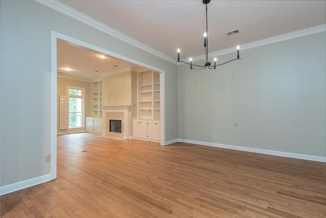 1060 Island Dr, Memphis, TN 38103 - unfurnished living room with ornamental molding, a chandelier, baseboards, light wood-style floors, and built in features