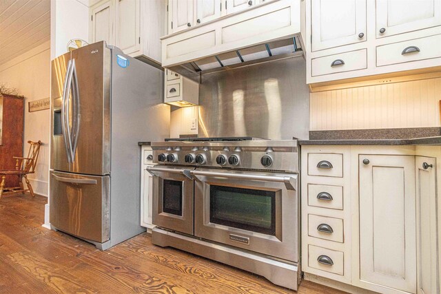 504 Rushing Rd, Michie, TN 38357 - kitchen featuring appliances with stainless steel finishes, wood finished floors, dark countertops, cream cabinets, and under cabinet range hood