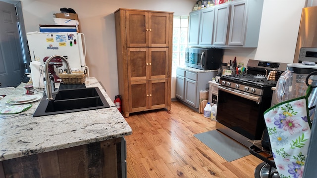 2304 Longstreet Dr, Memphis, TN 38114 - kitchen with appliances with stainless steel finishes, a sink, light wood finished floors, and brown cabinets