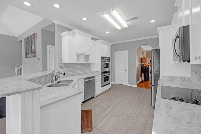 546 Township Cv, Collierville, TN 38017 - kitchen with appliances with stainless steel finishes, a sink, arched walkways, white cabinets, and a peninsula