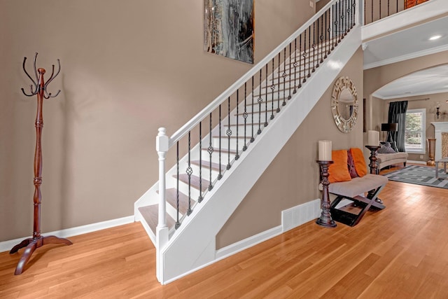546 Township Cv, Collierville, TN 38017 - staircase featuring arched walkways, ornamental molding, wood finished floors, baseboards, and a towering ceiling