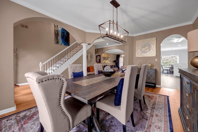 546 Township Cv, Collierville, TN 38017 - dining room with arched walkways, light wood-style floors, crown molding, stairs, and a chandelier