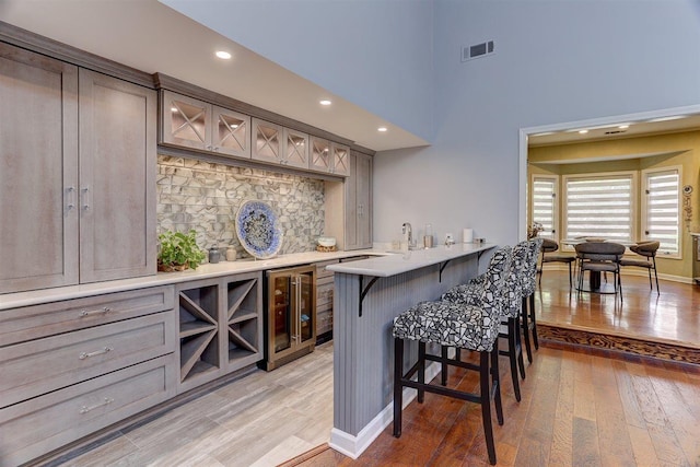 6703 N Kirby Oaks Cv, Memphis, TN 38119 - indoor dry bar featuring wine cooler, light wood-style floors, baseboards, recessed lighting, and a towering ceiling