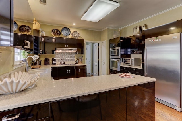 6703 N Kirby Oaks Cv, Memphis, TN 38119 - kitchen with appliances with stainless steel finishes, a sink, ornamental molding, under cabinet range hood, and a peninsula