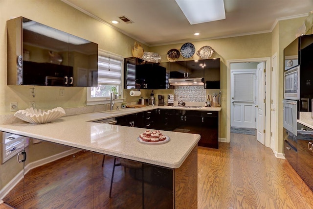 6703 N Kirby Oaks Cv, Memphis, TN 38119 - kitchen featuring a sink, light wood-style floors, crown molding, under cabinet range hood, and a peninsula