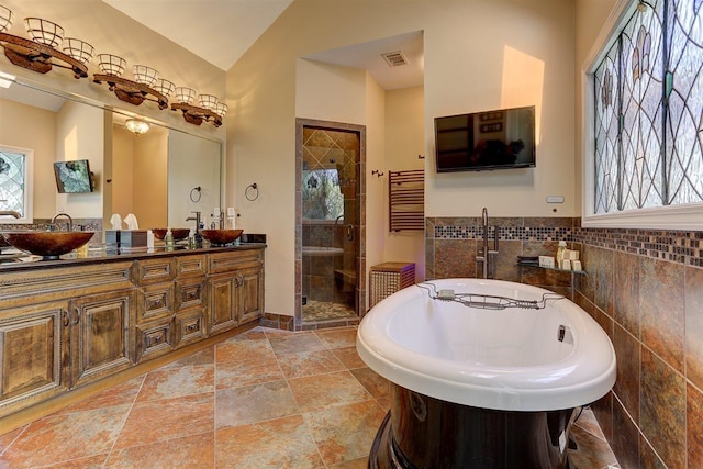 6703 N Kirby Oaks Cv, Memphis, TN 38119 - bathroom with a soaking tub, double vanity, a shower stall, stone tile floors, and tile walls