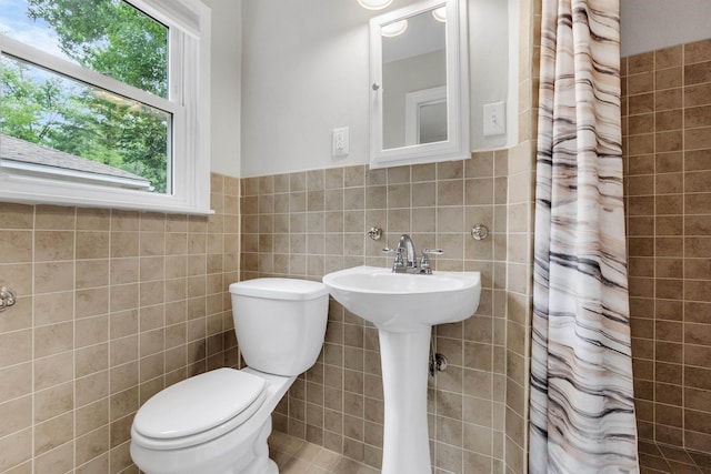 5251 Sequoia Ave, Memphis, TN 38120 - bathroom featuring tile walls, toilet, healthy amount of natural light, curtained shower, and wainscoting