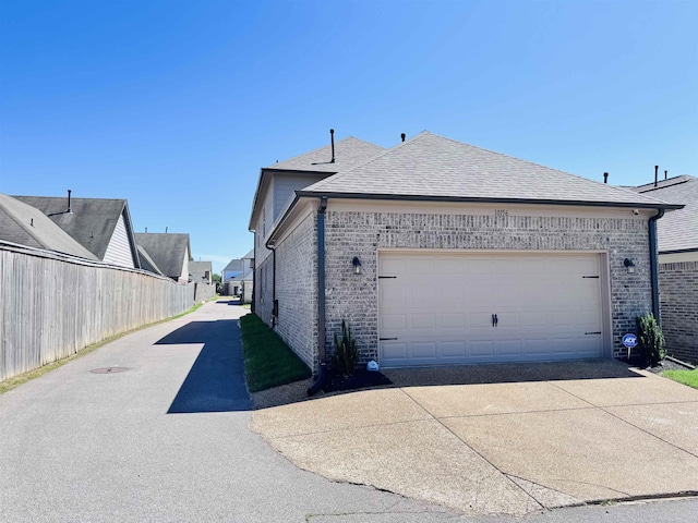 10156 Amberton Cv, Cordova, TN 38018 - view of home's exterior featuring driveway, brick siding, roof with shingles, and an attached garage
