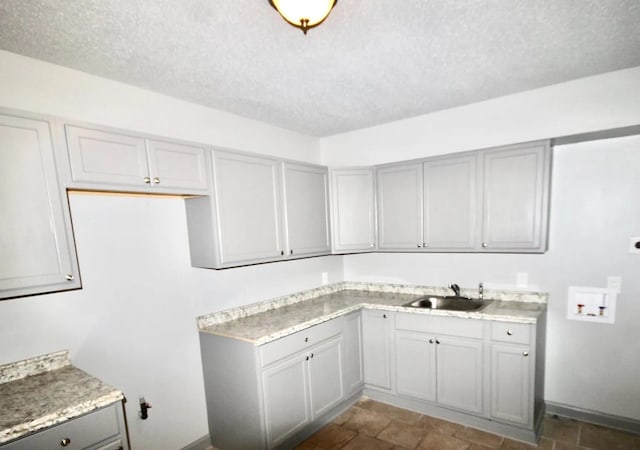 487 Williams Ave, Memphis, TN 38126 - laundry room featuring hookup for a washing machine, a textured ceiling, cabinet space, dark stone finish flooring, and baseboards