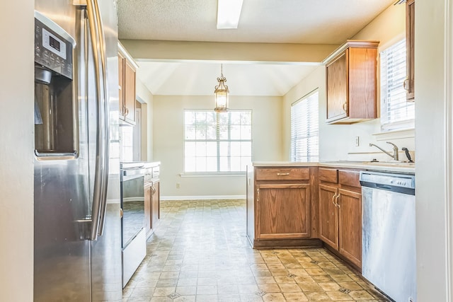 1168 E Red Fern Cir, Cordova, TN 38018 - kitchen with stainless steel appliances, a sink, light countertops, brown cabinetry, and pendant lighting