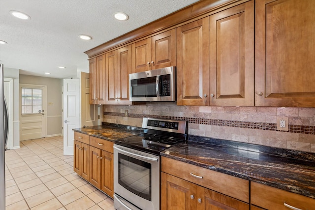 7617 Hollow Fork Rd, Germantown, TN 38138 - kitchen with stainless steel appliances, light tile patterned floors, brown cabinets, recessed lighting, and decorative backsplash