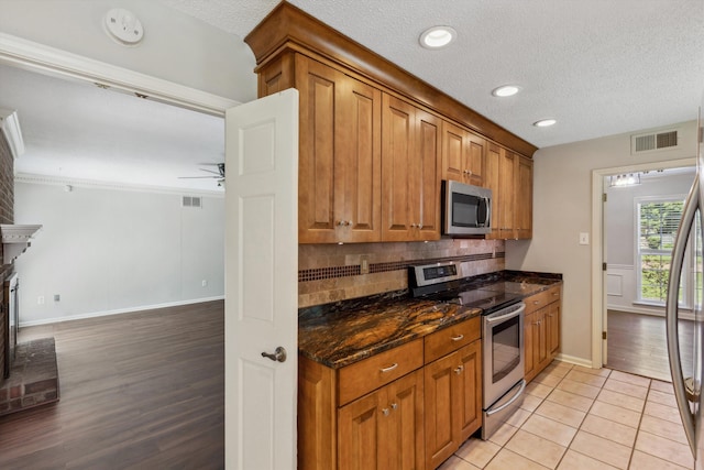 7617 Hollow Fork Rd, Germantown, TN 38138 - kitchen featuring appliances with stainless steel finishes, baseboards, brown cabinetry, tasteful backsplash, and a textured ceiling