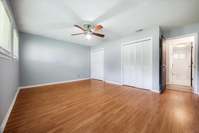 5796 N Foxburrow Cir, Memphis, TN 38115 - unfurnished bedroom with multiple windows, two closets, light wood-type flooring, and baseboards