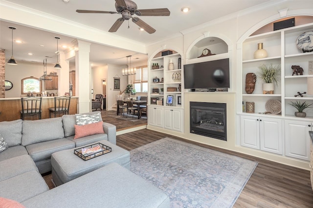 1245 Auburn Woods Dr, Collierville, TN 38017 - living room with dark wood-type flooring, ceiling fan, crown molding, a glass covered fireplace, and a chandelier