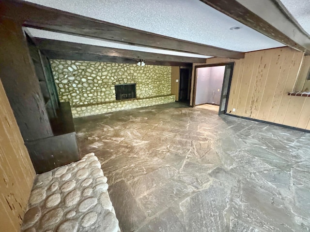 3751 Lakewood Dr N, Memphis, TN 38128 - unfurnished living room with beamed ceiling, a fireplace, wooden walls, baseboards, and a textured ceiling