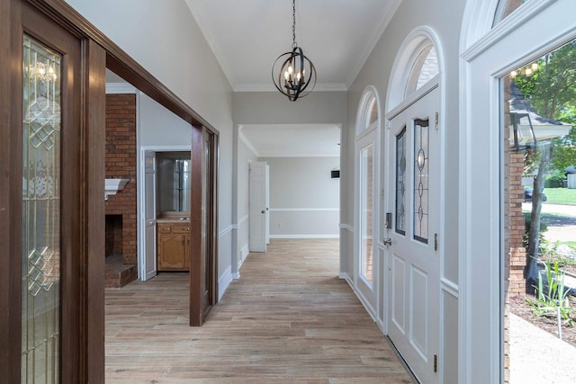 8432 Wood Shadows Ln, Memphis, TN 38018 - foyer with a chandelier, light wood-style flooring, ornamental molding, and a brick fireplace