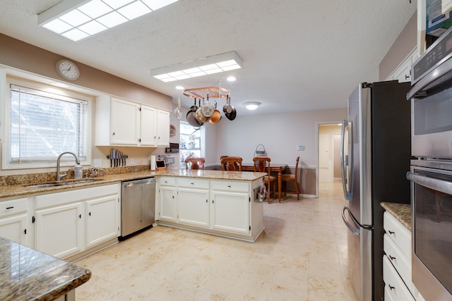167 Ericson Rd, Memphis, TN 38018 - kitchen featuring a sink, stainless steel appliances, white cabinets, a peninsula, and a textured ceiling