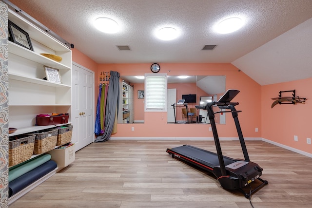 167 Ericson Rd, Memphis, TN 38018 - workout area featuring light wood-style flooring, a textured ceiling, baseboards, and lofted ceiling