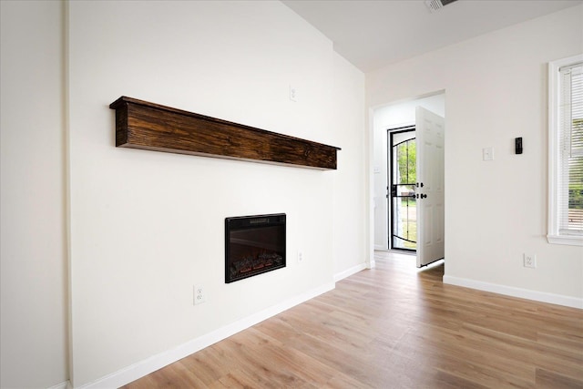 2551 Union Ave, Memphis, TN 38112 - unfurnished living room featuring light wood-style flooring, a glass covered fireplace, and baseboards