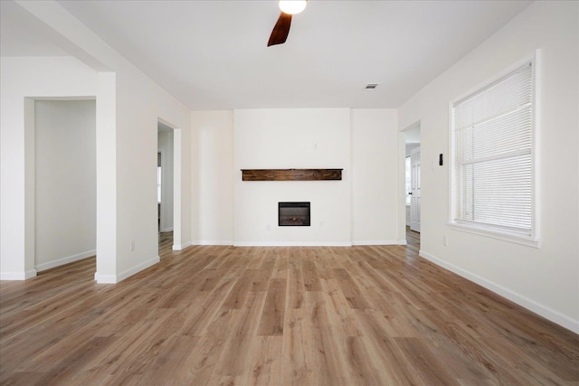 2551 Union Ave, Memphis, TN 38112 - unfurnished living room featuring ceiling fan, light wood-style flooring, a glass covered fireplace, and baseboards