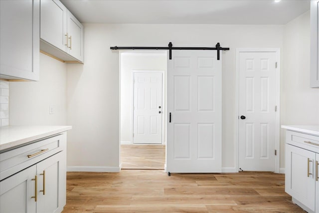 2551 Union Ave, Memphis, TN 38112 - kitchen with light wood-type flooring, light countertops, a barn door, and baseboards