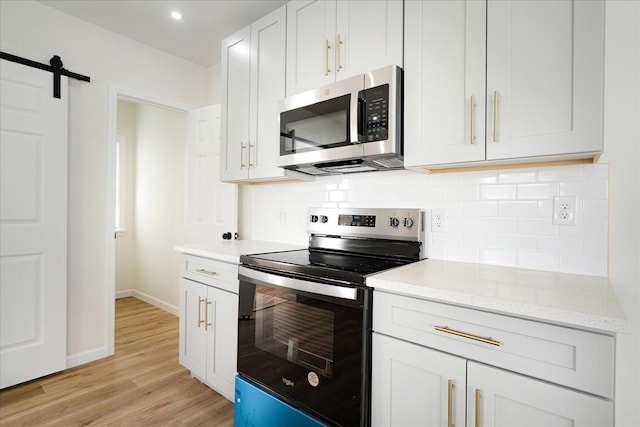 2551 Union Ave, Memphis, TN 38112 - kitchen featuring appliances with stainless steel finishes, tasteful backsplash, light wood-type flooring, light stone countertops, and baseboards