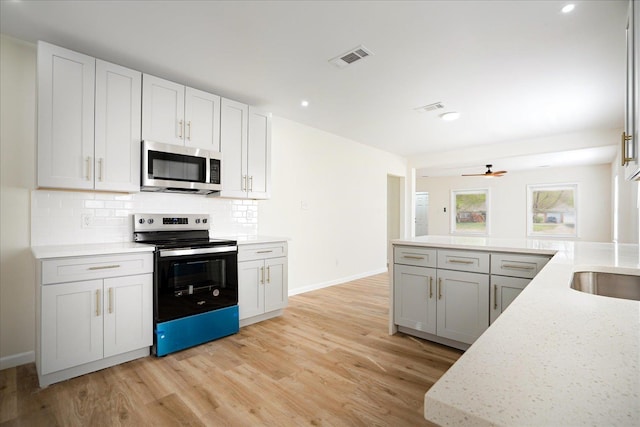2551 Union Ave, Memphis, TN 38112 - kitchen featuring stainless steel microwave, electric stove, light wood-type flooring, backsplash, and baseboards