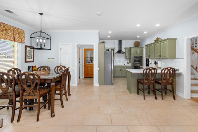 1620 Saddle Chase Cv, Memphis, TN 38016 - kitchen featuring green cabinetry, appliances with stainless steel finishes, wall chimney range hood, ornamental molding, and decorative backsplash
