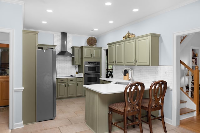 1620 Saddle Chase Cv, Memphis, TN 38016 - kitchen featuring wall chimney exhaust hood, stainless steel appliances, green cabinetry, a peninsula, and a sink