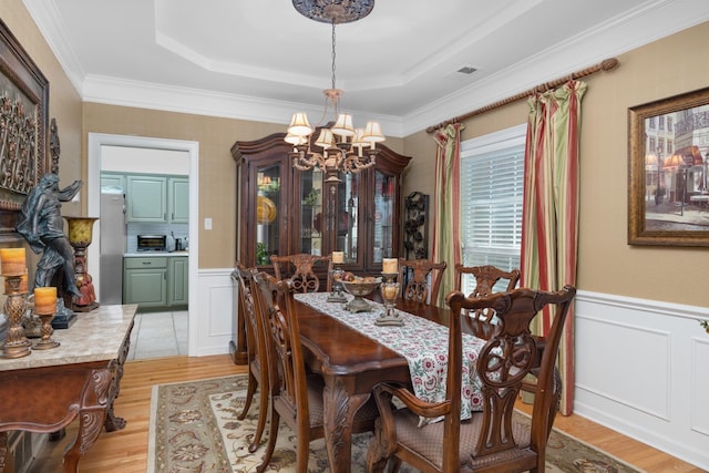 1620 Saddle Chase Cv, Memphis, TN 38016 - dining space with a chandelier, light wood-type flooring, a decorative wall, a tray ceiling, and wainscoting