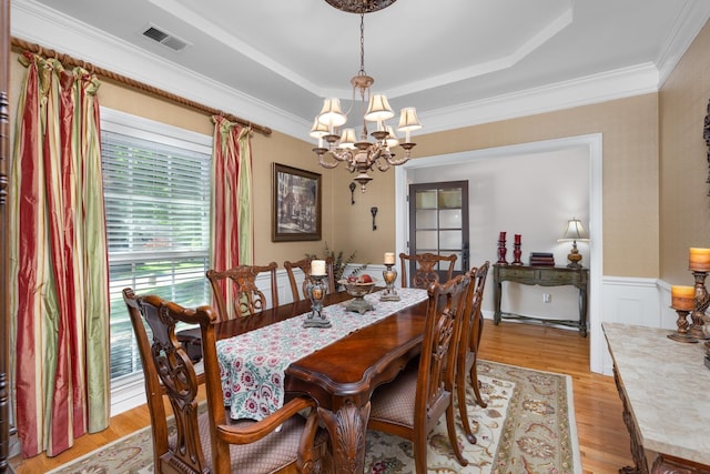 1620 Saddle Chase Cv, Memphis, TN 38016 - dining area with a chandelier, a tray ceiling, light wood finished floors, a wainscoted wall, and crown molding