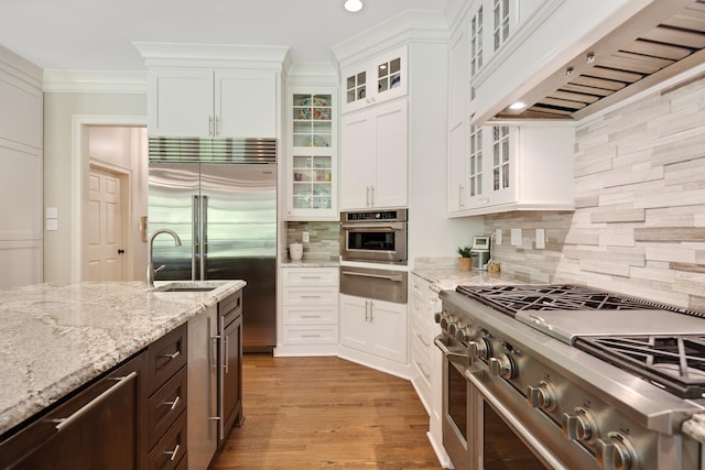 7726 Chapel Creek Pkwy N, Memphis, TN 38016 - kitchen with premium appliances, under cabinet range hood, a warming drawer, white cabinets, and tasteful backsplash