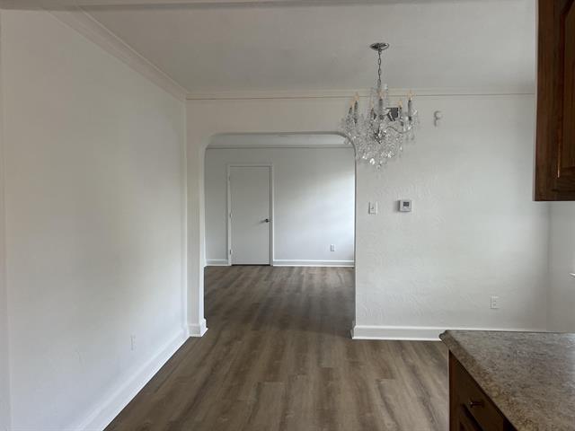 760 E Mckellar Ave, Memphis, TN 38106 - unfurnished dining area featuring dark wood-type flooring, baseboards, arched walkways, a chandelier, and ornamental molding